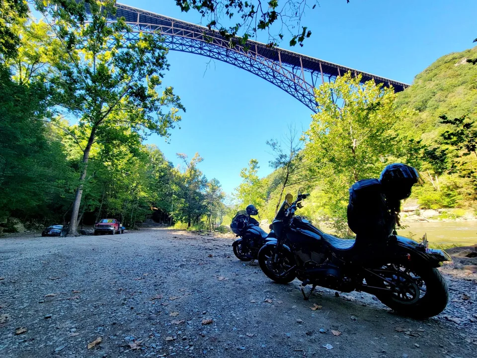 Touring motorcycles beside the river beneath the New River Gorge Bridge